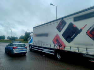 Zdjęcie kolorowe przedstawiające pojazd ciężarowy Man i radiowóz.