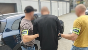 Zdjęcie kolorowe przedstawiające policjantów z zatrzymanym.