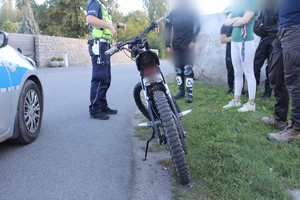 Zdjęcie kolorowe przedstawiające policjanta podczas kontroli drogowej jednośladu.