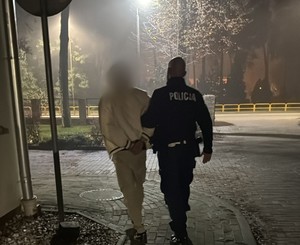Zdjęcie przedstawia zatrzymanego z policjantem.