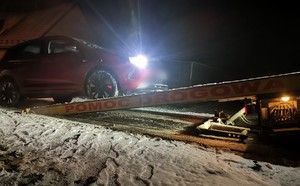 Zdjęcie przedstawia pojazd osobowy który jest wciągany na holownik.