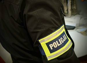 Zdjęcie przedstawia ramię mężcz6yzny z opaską odblaskową "Policja"