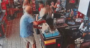 Zdjęcie przedstawia próbę zatrzymania mężczyzny, który chciał ukraść towar przez pracownicę marketu oraz klienta marketu.