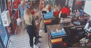 Zdjęcie przedstawia próbę zatrzymania mężczyzny, który chciał ukraść towar przez pracownicę marketu oraz klienta marketu.