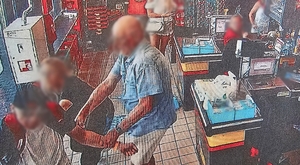 Zdjęcie przedstawia próbę zatrzymania mężczyzny, który chciał ukraść towar przez pracownicę marketu oraz klienta marketu.