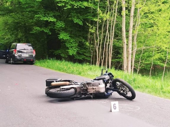 Zdjęcie przedstawia motocykl leżący na ziemi, po zdarzeniu drogowym.