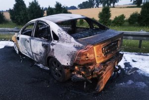 Zdjęcie przedstawia pojazd, który po uderzeniu w barierki ochronne zapalił się.