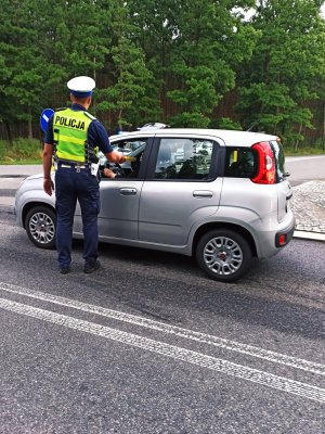 Zdjęcie przedstawia policjanta wydziału ruchu drogowego w trakcie badania stanu trzeźwości.