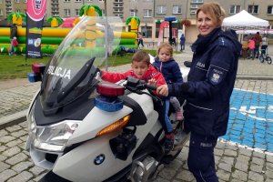 dwoje dzieci siedzi na policyjnym motocyklu, towarzyszy im policjantka