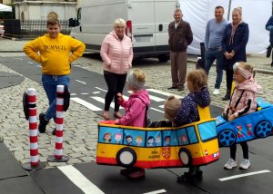 grupa dzieci porusza się po miasteczku ruchu drogowego w zabawkowym autobusie