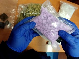 policjant trzyma w rękach tabletki ekstazy