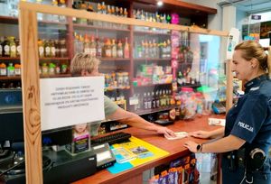 policjantka w sklepie monopolowym rozmawia ze sprzedawcą na temat obowiązujących przepisów odnośnie sprzedaży alkoholu i wyrobów tytoniowych nieletnim