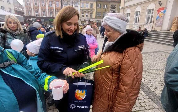 Kolorowe zdjęcie policjantki rozdającej opaski odblaskowe