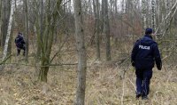 Policjanci chodzą po lesie i szukają poszukiwanego mężczyznę, który uciekł z konwoju.