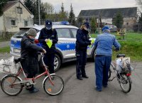 Policjanci rozdają elementy odblaskowe rowerzystom.