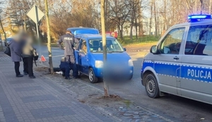 Zdjęcie przedstawia policjantów wymieniających koło w samochodzie.