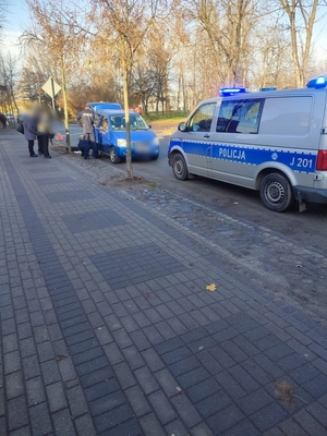 Zdjęcie przedstawia policjantów wymieniających koło w samochodzie.