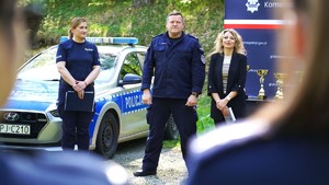 Policjanci na tle baneru, obok nich puchary.