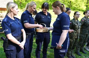 Policjantki stoją w rzędzie, jedna losuje numer strzelecki.