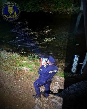 Zdjęcie: policjant kontroluje nocą poziom wody.