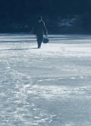 zdjęcie: zamarznięty staw i wędkarz na nim przebywający