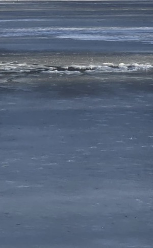 zdjęcie: zamarznięty staw i wędkarz na nim przebywający