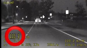 kadr z nagrania wideorejestratora policyjnego, widoczny samochód osobowy, wskazanie z ekranu wideorejestratora 116km/h, wczesny poranek, ciemno, odbijające się znaki drogowe