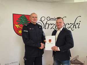 Fotografia przedstawia Komendanta Powiatowego Policji oraz Burmistrza. Wspólnie trzymają zawarte porozumienie w sprawie dodatkowych środków na dodatkowe patrole Policji w gminie.