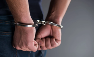 Zdjęcie obrazuje ręce mężczyzny, który ma założone kajdanki