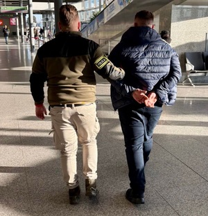 zdjęcie: policjant z zatrzymanym na lotnisku