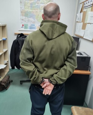 Fotografia przedstawia mężczyznę, który ma założone kajdanki