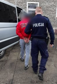 policjant, samochód koloru srebrnego, zatrzymany mężczyzna w czerwonej kurtce i szarych spodniach