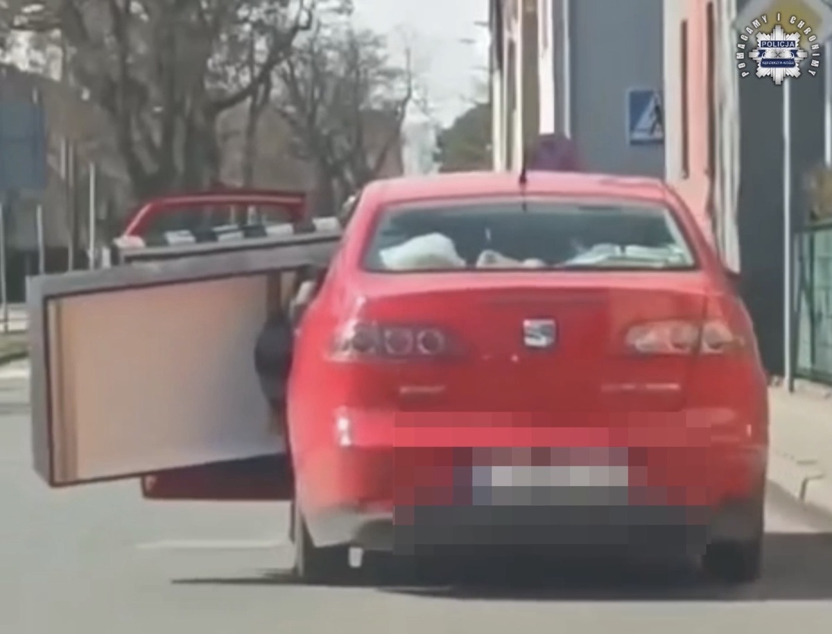 czerwony seat który wiezie na tylnym siedzeniu kanapę z otwartymi drzwiami