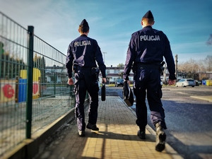na zdjęciu dwóch policjantów idących chodnikiem