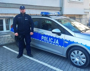 Zdjęcie kolorowe: mężczyzna stojący przy radiowozie.