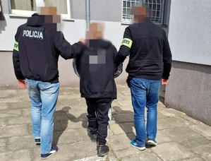 Trzech mężczyzn idzie obok siebie, dwóch z nich ma na odzieży wierzchniej napis Policja.