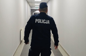 zdjęcie kolorowe - postać policjanta idącego korytarzem