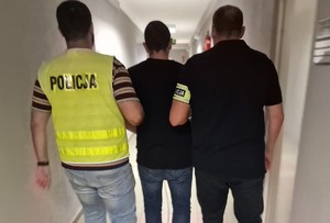 zdjęcie kolorowe - dwóch funkcjonariuszy prowadzi zatrzymanego meżczyznę