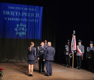 zdjęcie kolorowe - przedstawiające sylwetki funkcjonariuszy na scenie