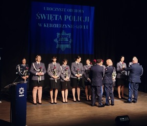 zdjęcie kolorowe - przedstawiające sylwetki funkcjonariuszy na scenie