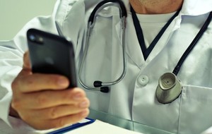 zdjęcie kolorowe - lekarz trzymający telefon komórkowy