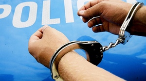 zdjęcie kolorowe- ręce zakute w kajdanki na tle radiowowzu