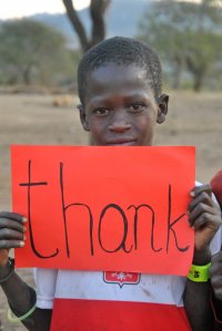 Chłopiec z Tanzanii trzyma w ręce kartkę z napisem thank