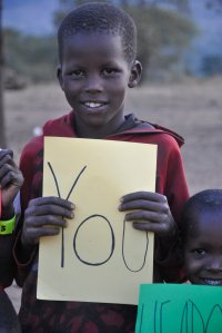 Chłopiec z Tanzanii trzyma w ręce kartkę z napisem You
