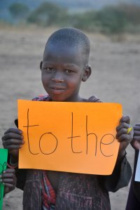 Chłopiec z Tanzanii trzyma w ręce kartkę z napisem to the