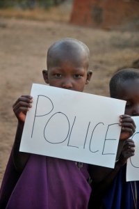 Chłopiec z Tanzanii trzyma w ręce kartkę z napisem Police