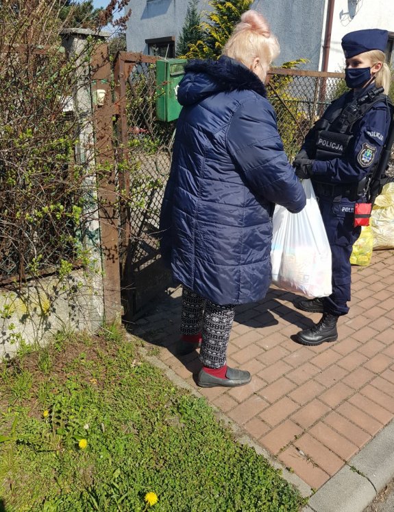 Policjantka i policjant wręczają paczki seniorom