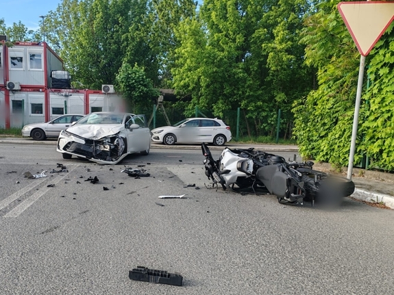 Zdjęcie przedstawia leżący na drodze samochód, obok motocykl.