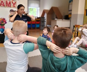 Policjantka razem z dziećmi wykonuje ćwiczenia fizyczne.