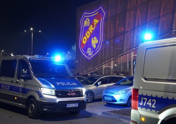 Radiowozy na tle stadionu.